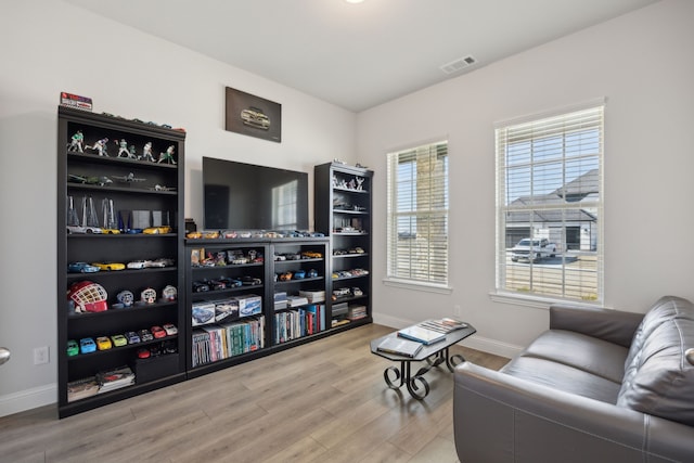 living area featuring baseboards, visible vents, and wood finished floors