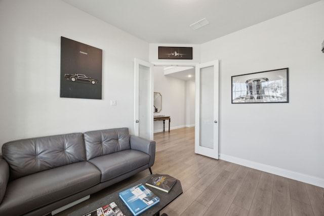 living area featuring light wood-type flooring, visible vents, and baseboards