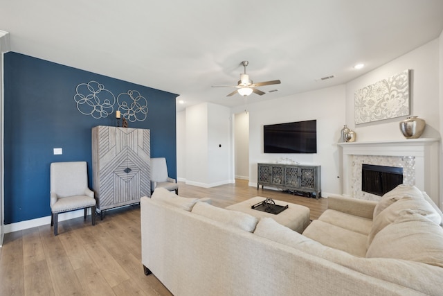 living area featuring recessed lighting, a ceiling fan, a high end fireplace, baseboards, and light wood-type flooring