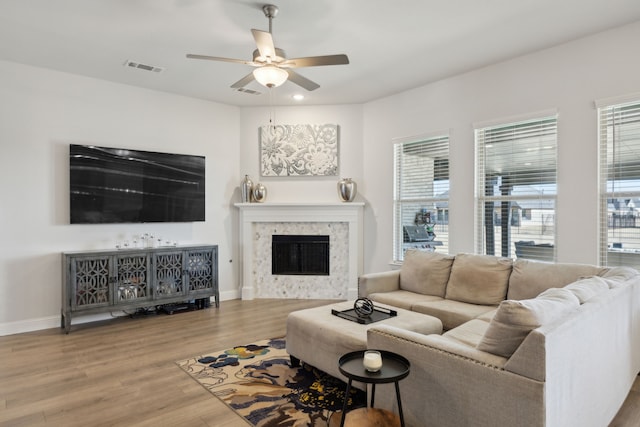 living room with baseboards, visible vents, a ceiling fan, wood finished floors, and a fireplace