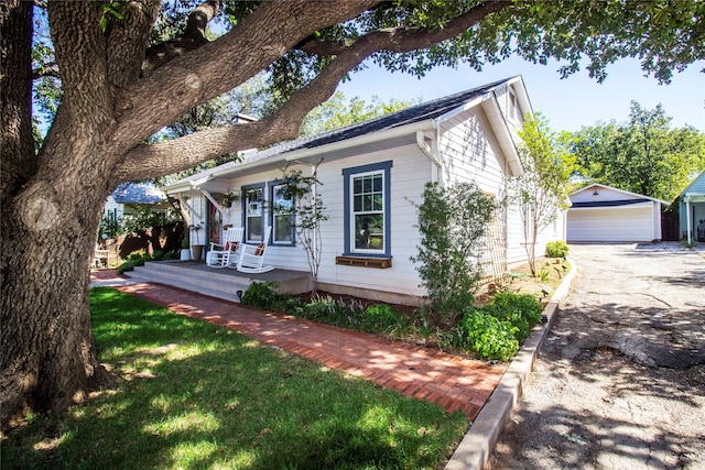 view of front facade featuring an outbuilding, covered porch, a garage, and a front yard