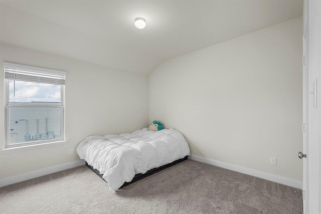 carpeted bedroom with lofted ceiling and baseboards