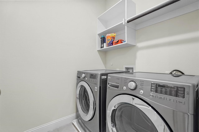 clothes washing area with baseboards, laundry area, and washer and dryer