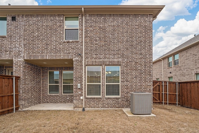 back of house with a patio, brick siding, a fenced backyard, and central air condition unit