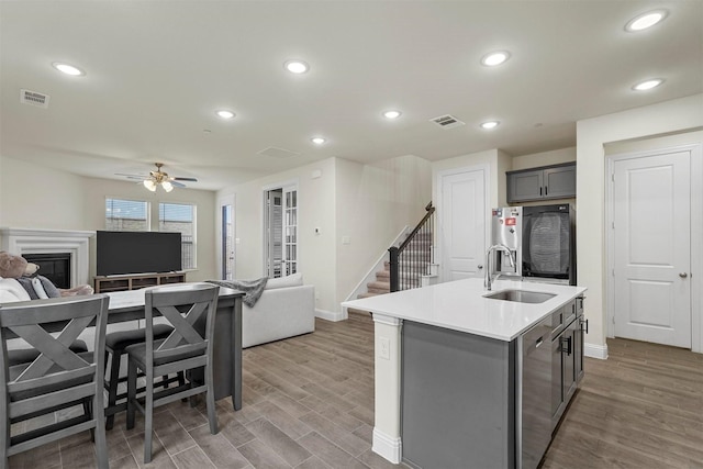 kitchen featuring visible vents, gray cabinets, a sink, and open floor plan