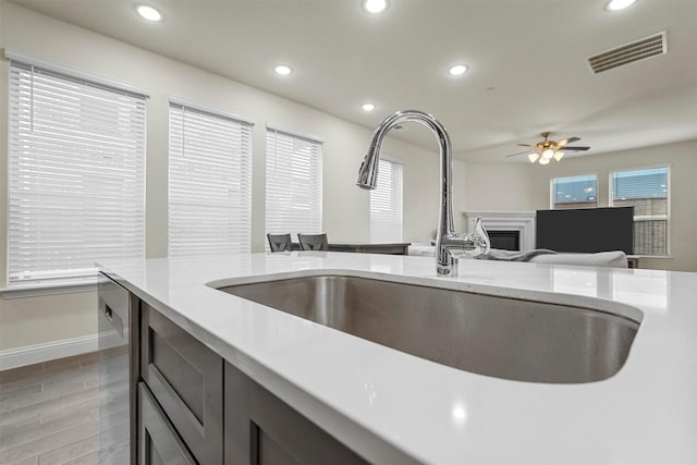 kitchen featuring recessed lighting, a fireplace, a sink, visible vents, and open floor plan