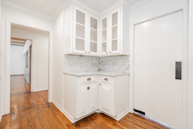 1265 S Main St, Jacksboro, TX 76458 - kitchen with backsplash, white cabinetry, glass insert cabinets, wood finished floors, and crown molding
