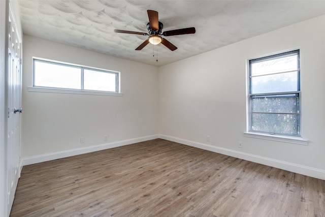 empty room with light wood finished floors, ceiling fan, and baseboards