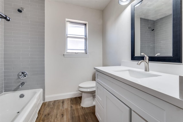 bathroom with baseboards, toilet, wood finished floors, vanity, and shower / washtub combination