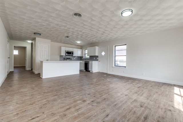 unfurnished living room featuring light wood-style floors, baseboards, and visible vents