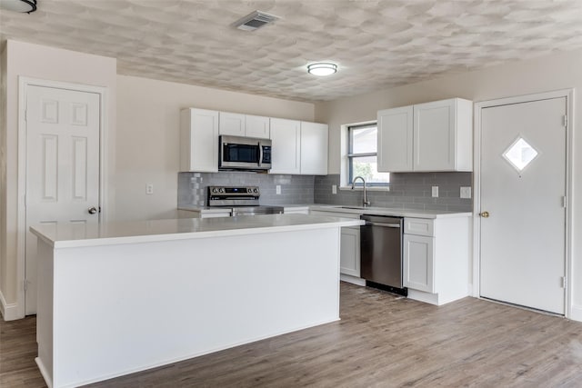 kitchen with visible vents, white cabinets, wood finished floors, stainless steel appliances, and light countertops