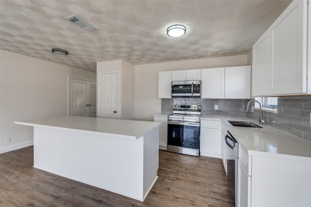 kitchen with dark wood-type flooring, a sink, visible vents, appliances with stainless steel finishes, and decorative backsplash