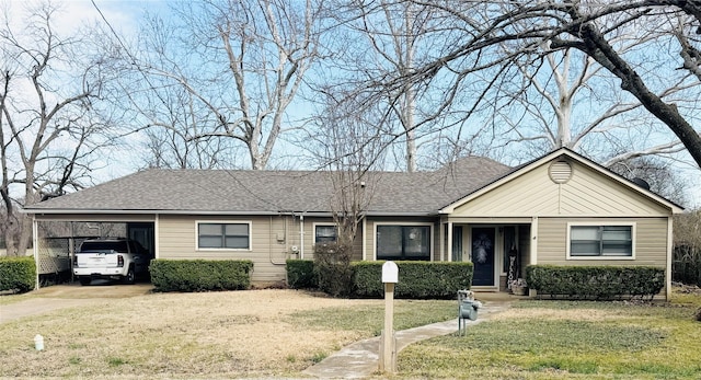 ranch-style house with driveway, an attached carport, roof with shingles, and a front yard