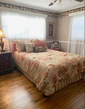 bedroom featuring multiple windows, a ceiling fan, and wood finished floors