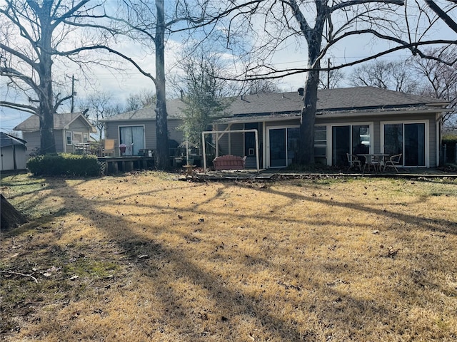 rear view of house with a shingled roof and a yard