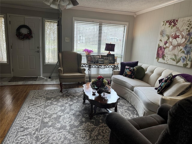 living room with a textured ceiling, wood finished floors, a ceiling fan, baseboards, and crown molding