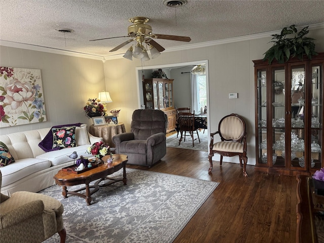 living area featuring a textured ceiling, wood finished floors, visible vents, and crown molding