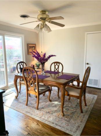 dining room with a ceiling fan, visible vents, dark wood-style flooring, and crown molding