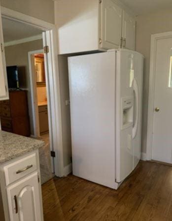 kitchen with white refrigerator with ice dispenser, wood finished floors, and white cabinets