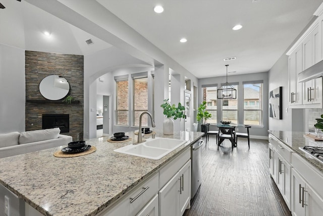 kitchen featuring visible vents, a fireplace, stainless steel appliances, a sink, and white cabinets