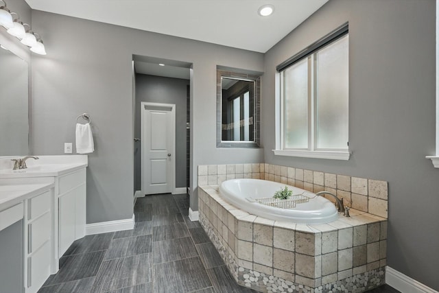 full bathroom featuring baseboards, vanity, and a garden tub