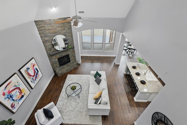 living area with visible vents, baseboards, a fireplace, wood finished floors, and arched walkways