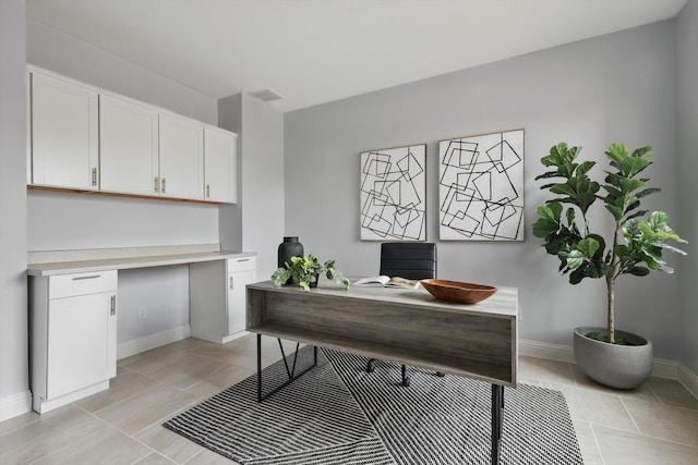 home office featuring light tile patterned floors, visible vents, baseboards, and built in study area