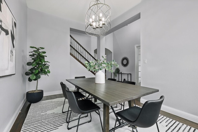 dining area featuring an inviting chandelier, stairs, baseboards, and wood finished floors