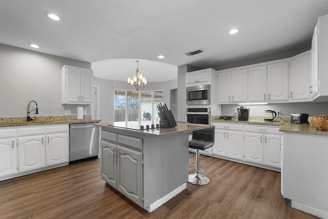 kitchen featuring visible vents, dark wood finished floors, appliances with stainless steel finishes, white cabinets, and a sink