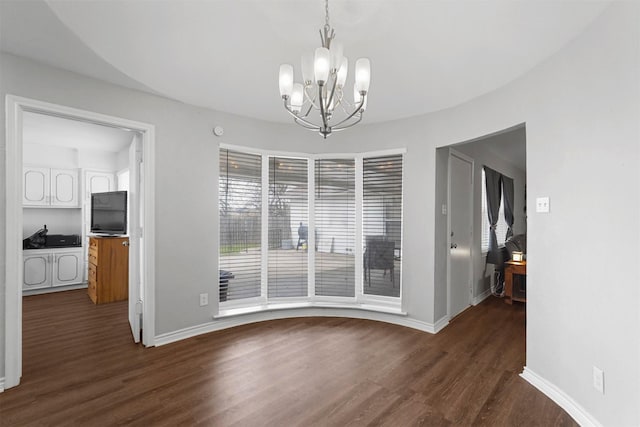 unfurnished dining area with a notable chandelier, dark wood-type flooring, and baseboards