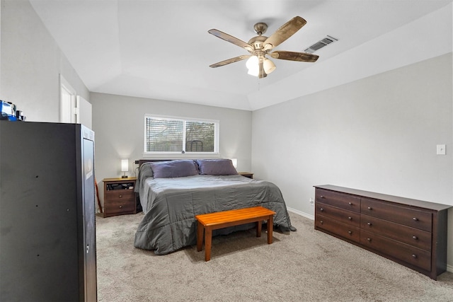 bedroom with baseboards, visible vents, ceiling fan, light carpet, and a raised ceiling