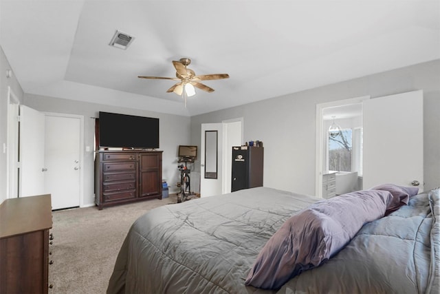 bedroom featuring a tray ceiling, visible vents, light colored carpet, and ceiling fan