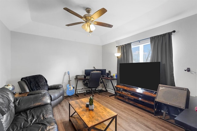 living area featuring a tray ceiling, wood finished floors, and a ceiling fan