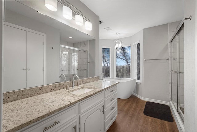 bathroom with vanity, wood finished floors, baseboards, a freestanding tub, and a stall shower