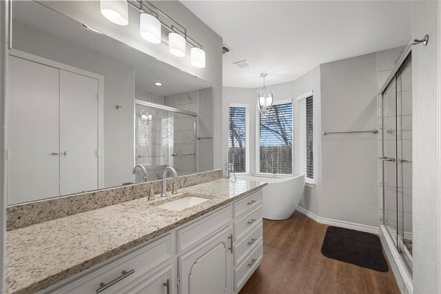 full bath featuring recessed lighting, a stall shower, an inviting chandelier, wood finished floors, and a soaking tub