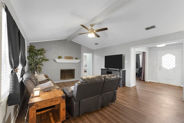 living room with visible vents, a brick fireplace, vaulted ceiling with beams, wood finished floors, and a ceiling fan