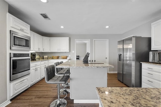 kitchen featuring stainless steel appliances, visible vents, a center island, and white cabinetry