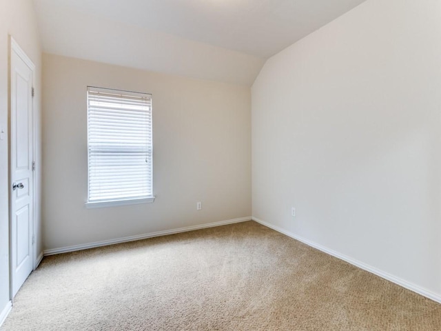 carpeted empty room with lofted ceiling and baseboards