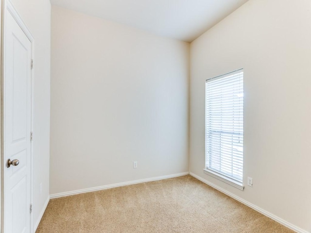 spare room featuring baseboards and light colored carpet