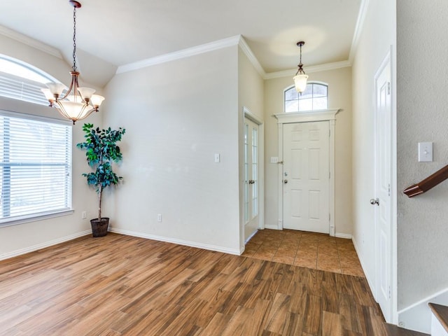 entrance foyer featuring baseboards, crown molding, an inviting chandelier, and wood finished floors