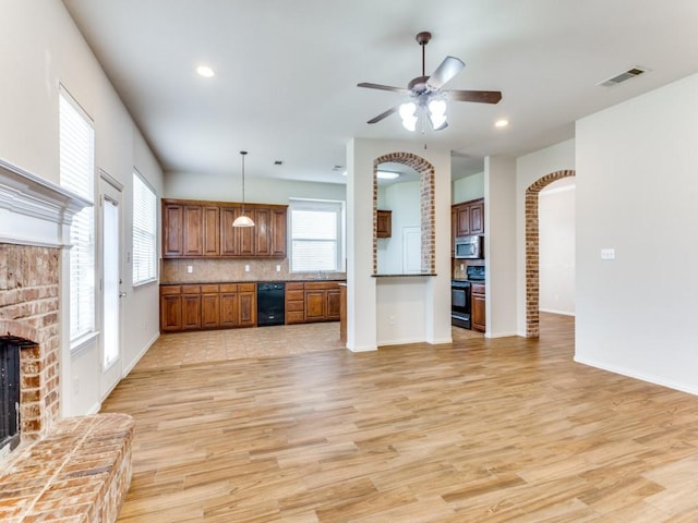 kitchen with a fireplace, visible vents, light wood-type flooring, black appliances, and brown cabinetry