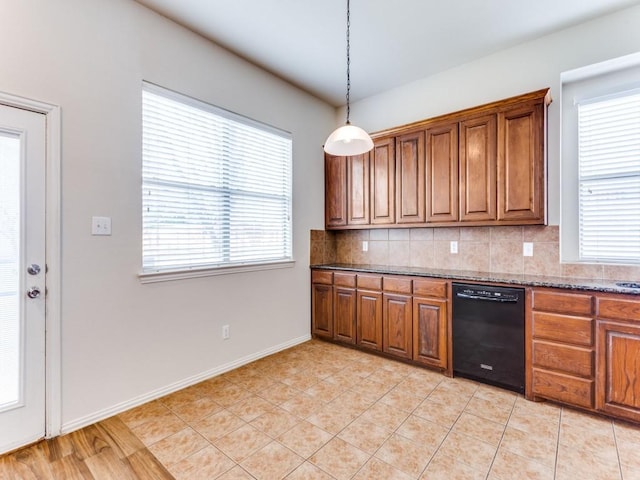 kitchen with black dishwasher, brown cabinetry, dark stone countertops, and backsplash