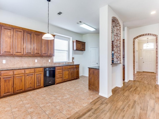 kitchen featuring black dishwasher, visible vents, decorative backsplash, arched walkways, and brown cabinets