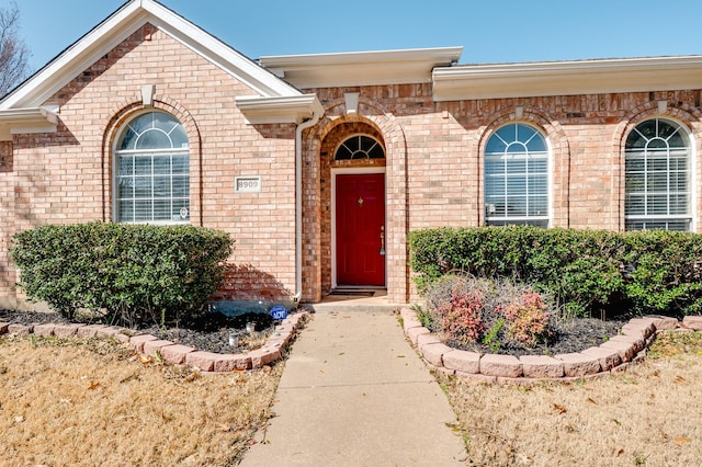 view of exterior entry featuring brick siding