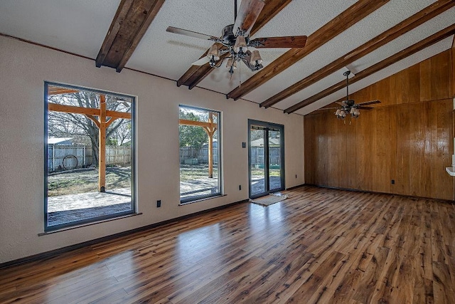 empty room with ceiling fan, wood finished floors, beam ceiling, and baseboards