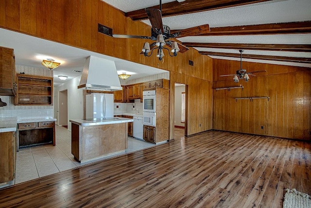 kitchen with white appliances, wood walls, a ceiling fan, and range hood