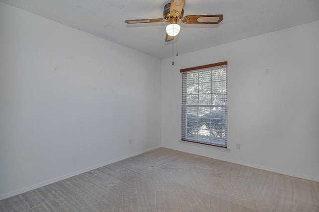 spare room with ceiling fan, baseboards, a textured ceiling, and light colored carpet