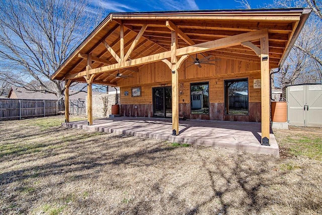 rear view of house with an outbuilding, a patio, a storage shed, fence, and ceiling fan