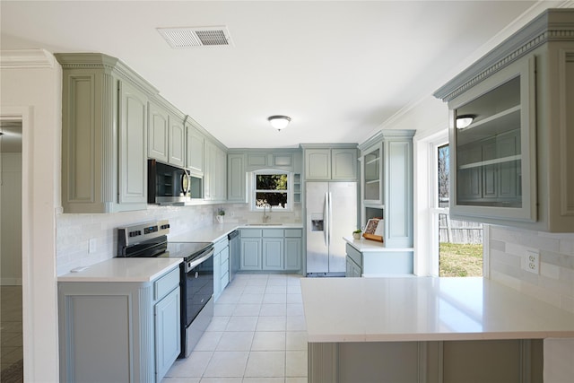 kitchen with light tile patterned floors, stainless steel appliances, a peninsula, a sink, and visible vents