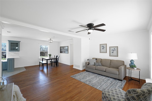 living room with baseboards, visible vents, wood finished floors, and ornamental molding